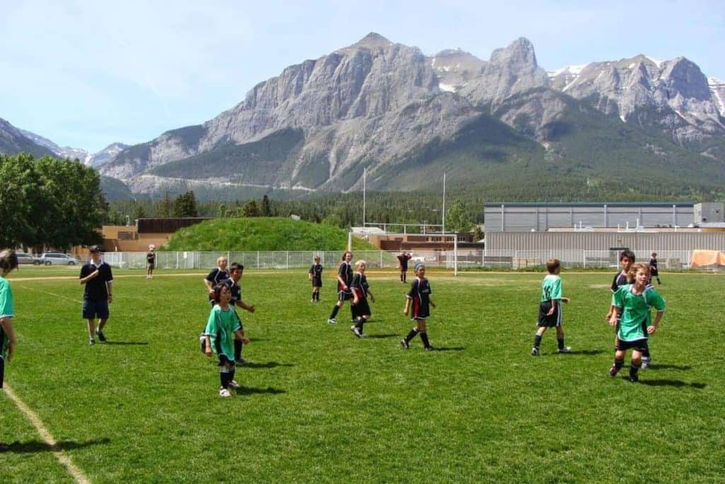 Partido de fútbol infantil de primavera frente a las montañas de tres hermanas Canmore Alberta. Deportes más populares en Canadá.