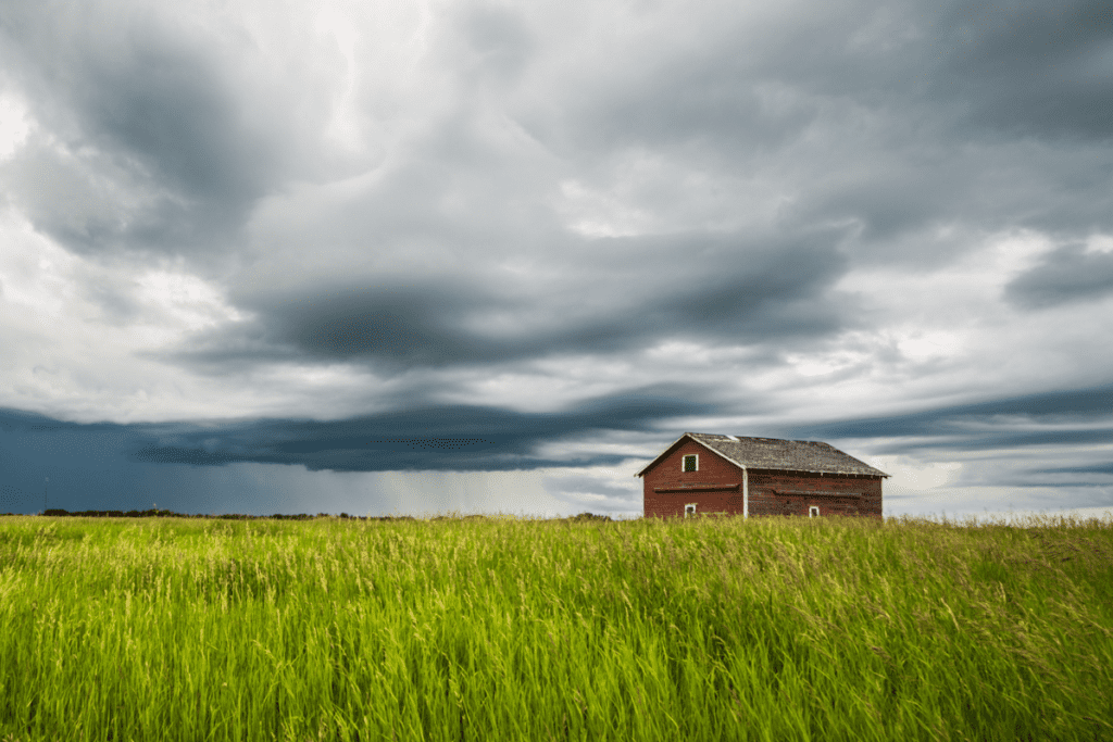 Vista de la pradera de verano de campos de trigo y un granero con un cielo tormentoso Pros y contras de vivir en Bon Accord Alberta Canadá