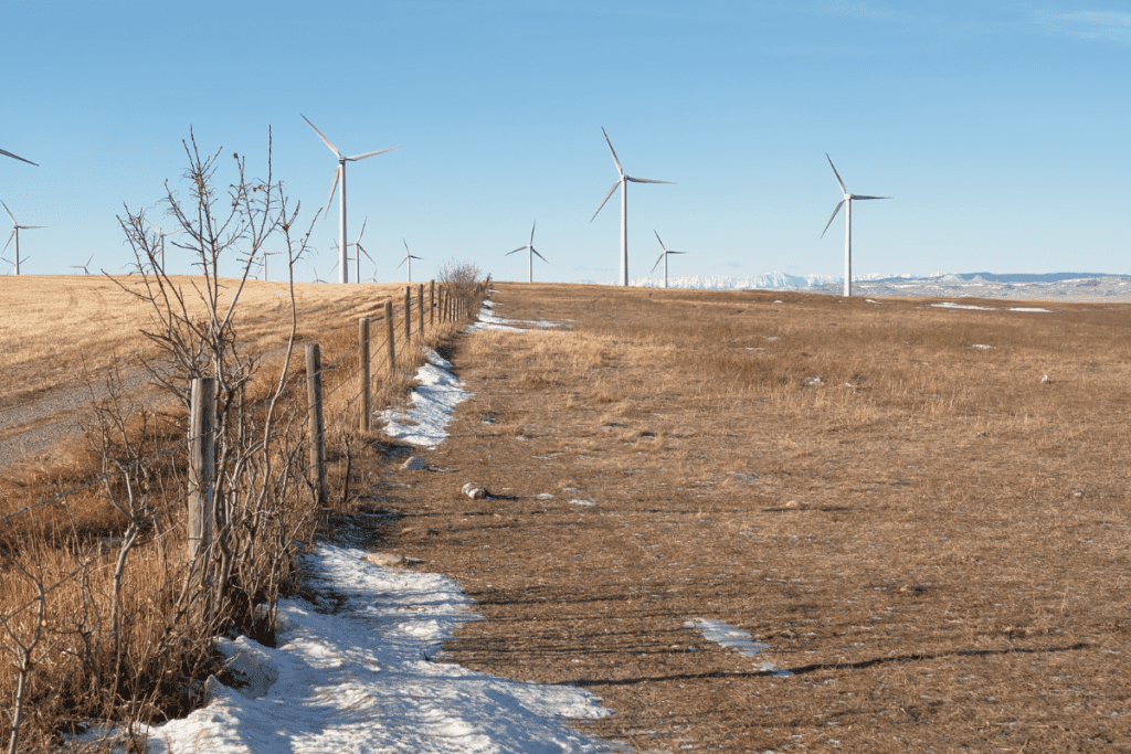 Turbinas eólicas en otoño en las praderas con vistas a las Montañas Rocosas, una de las mejores razones para mudarse a Alberta, Canadá
