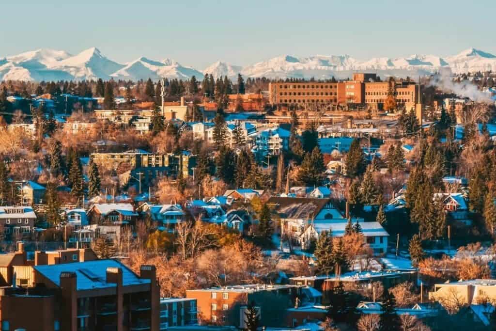 Zona de viviendas residenciales asequibles en Calgary con montañas cubiertas de nieve al fondo, una de las mejores razones para mudarse a Alberta, Canadá