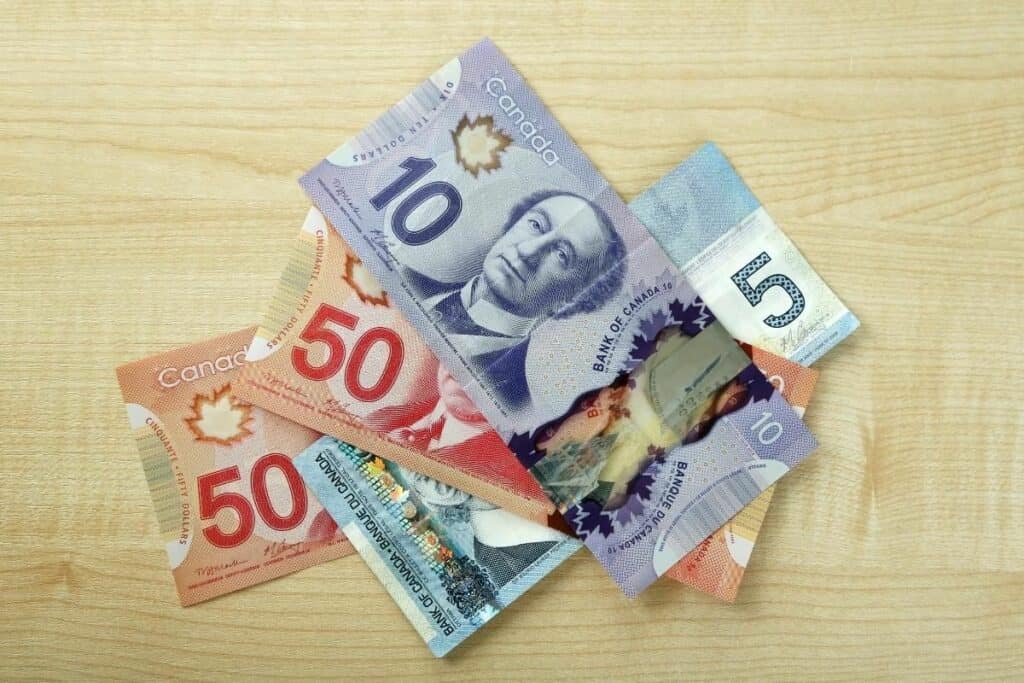 Billets de banque canadiens sur une table pour représenter les salaires élevés en Alberta, l'une des meilleures raisons de déménager en Alberta Canada